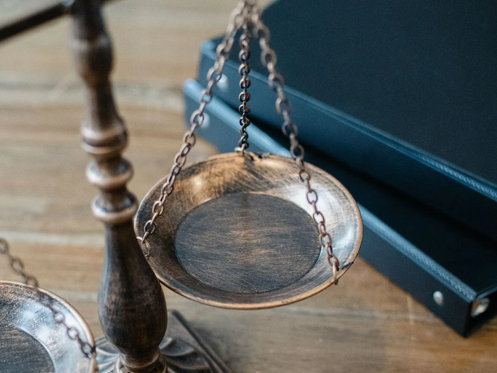 A bronze scale of justice and gavel resting on a wooden desk beside a legal book