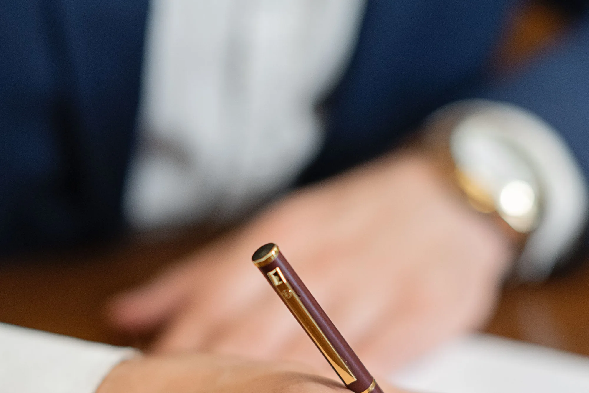 A close-up of a hand signing an insurance claim document with a fountain pen