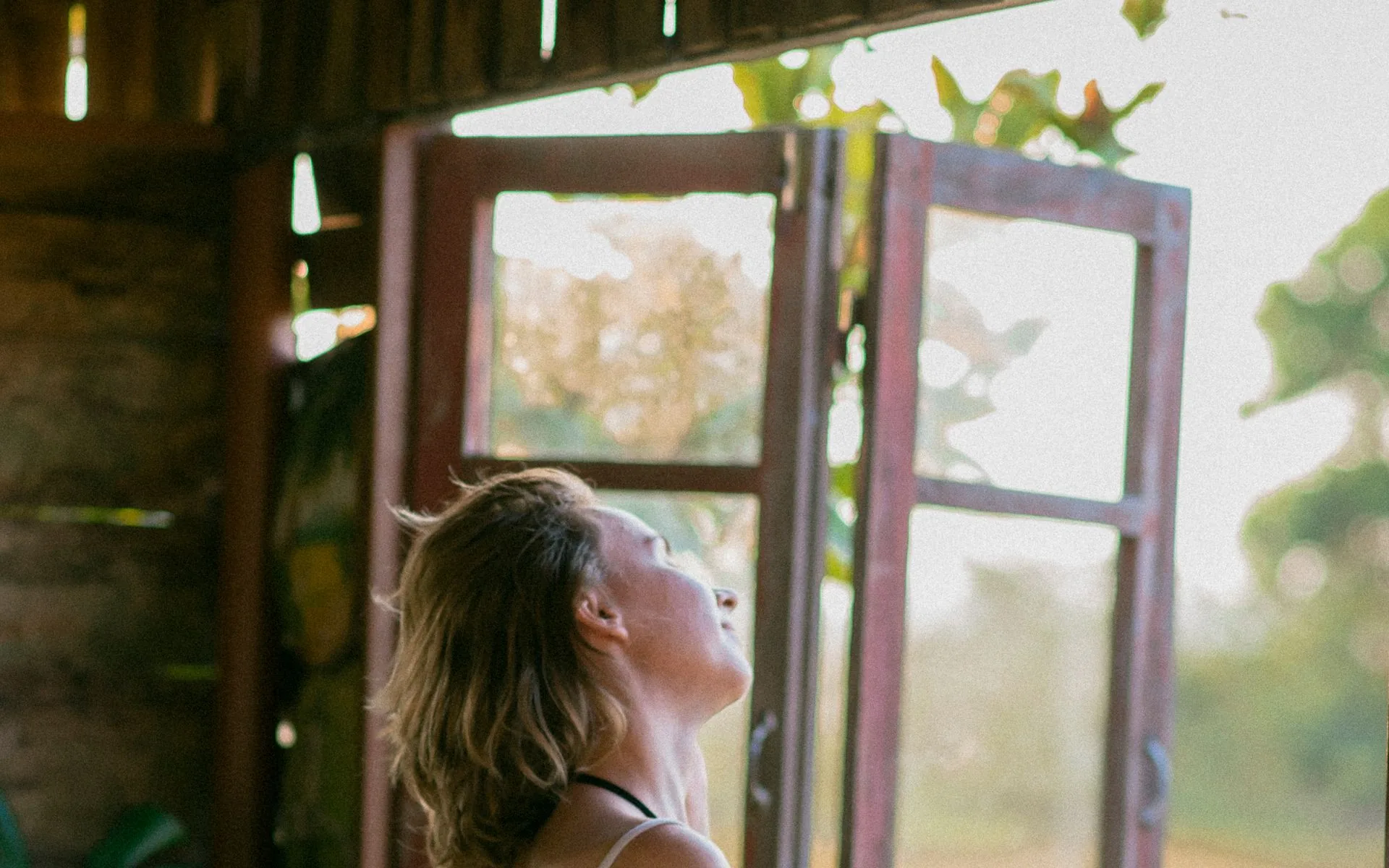 A woman breathing in fresh air from an open window