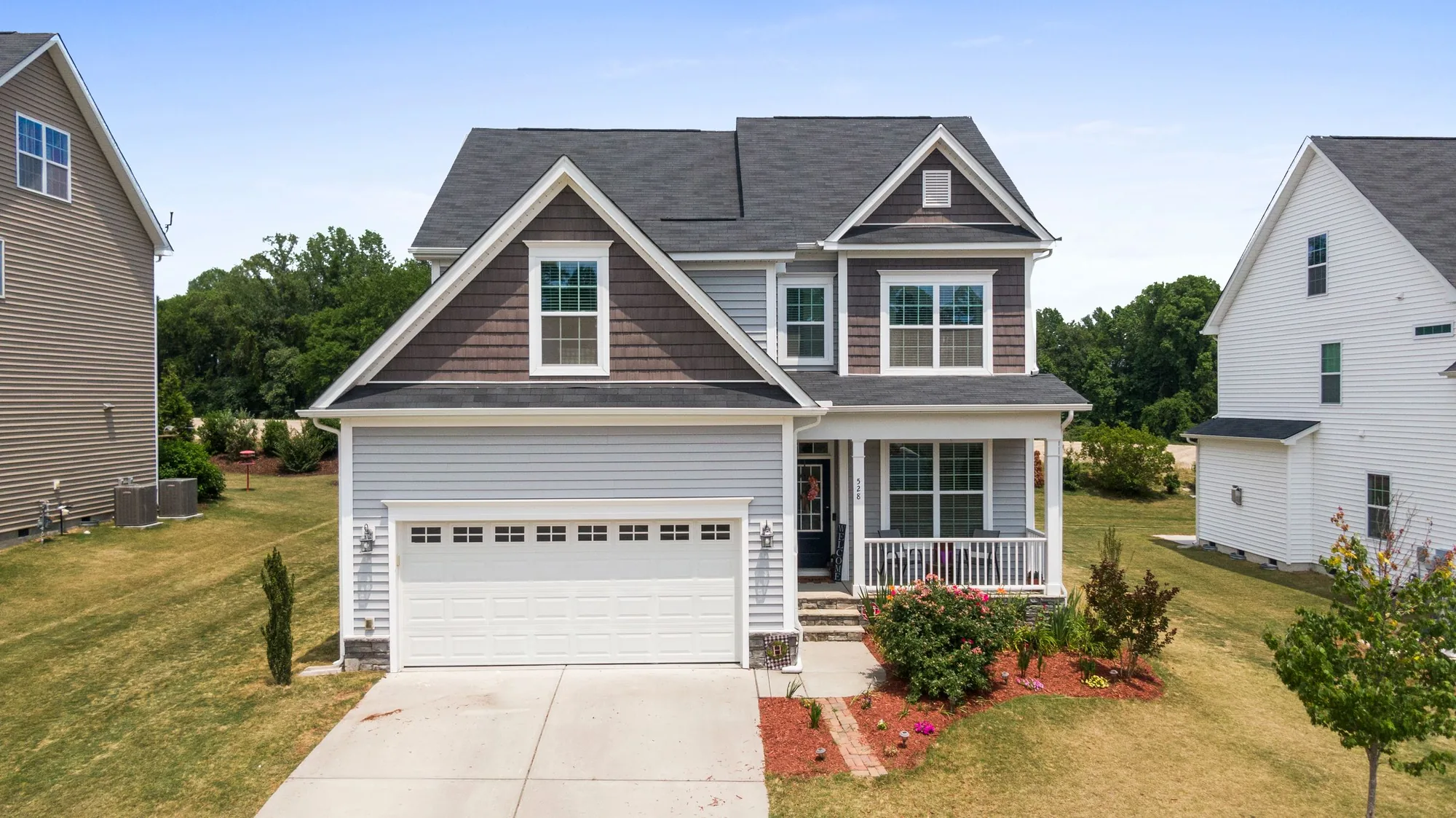 A two-story craftsman-style home in a newer Florida neighborhood with a welcome sign on the garage