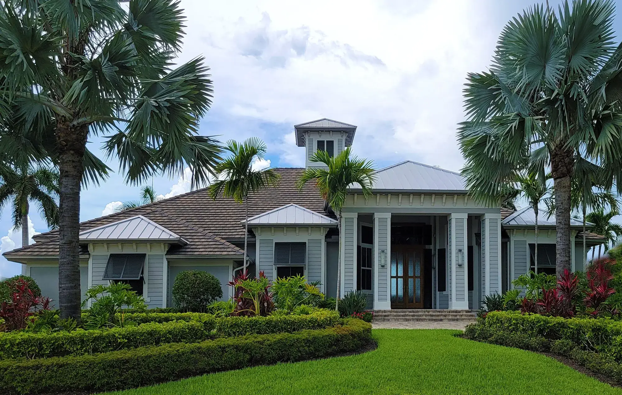 An upscale coastal Florida home with a tile roof, palm trees, and a covered entry