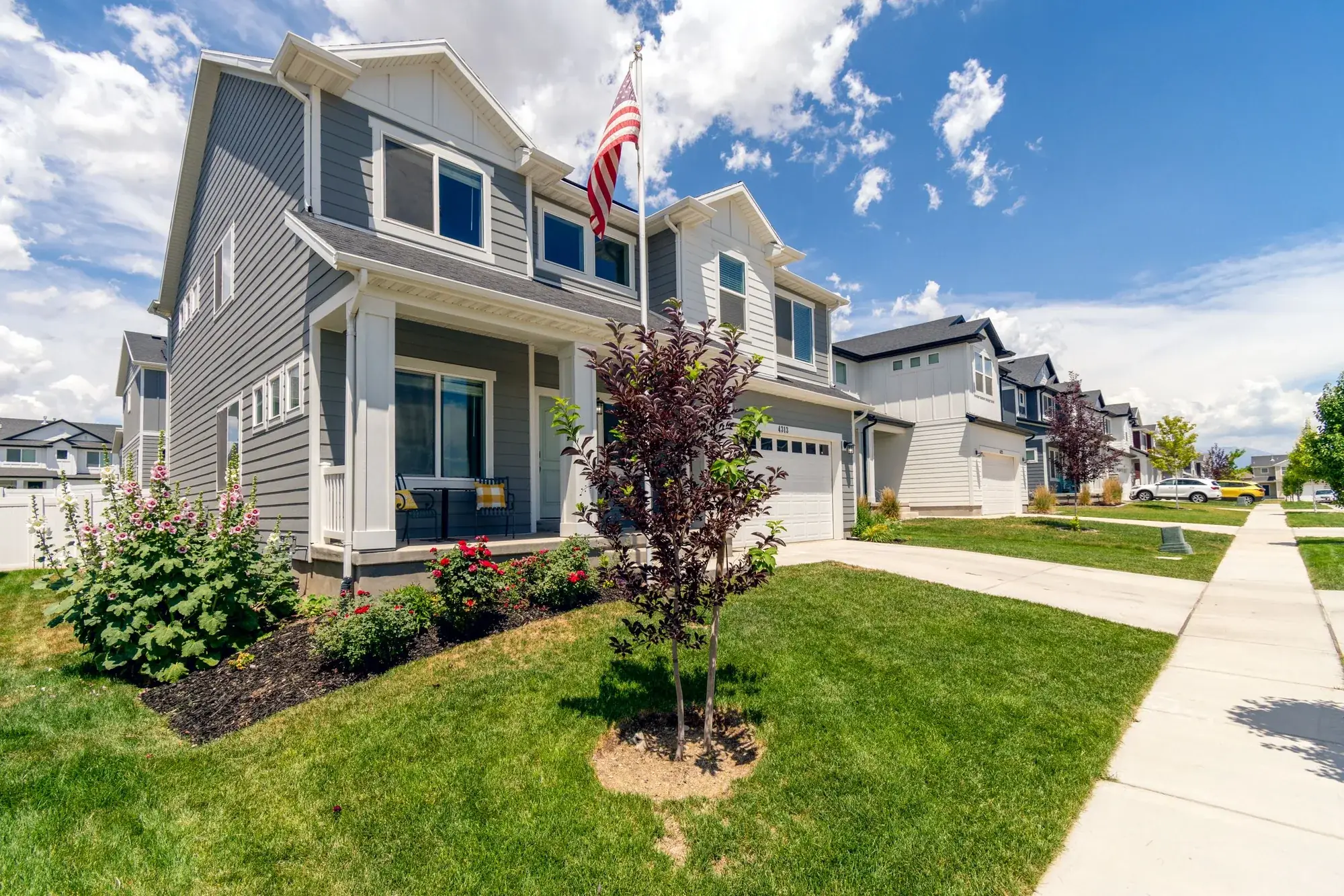 A two-story suburban Florida home with an American flag on the porch and a well-kept lawn