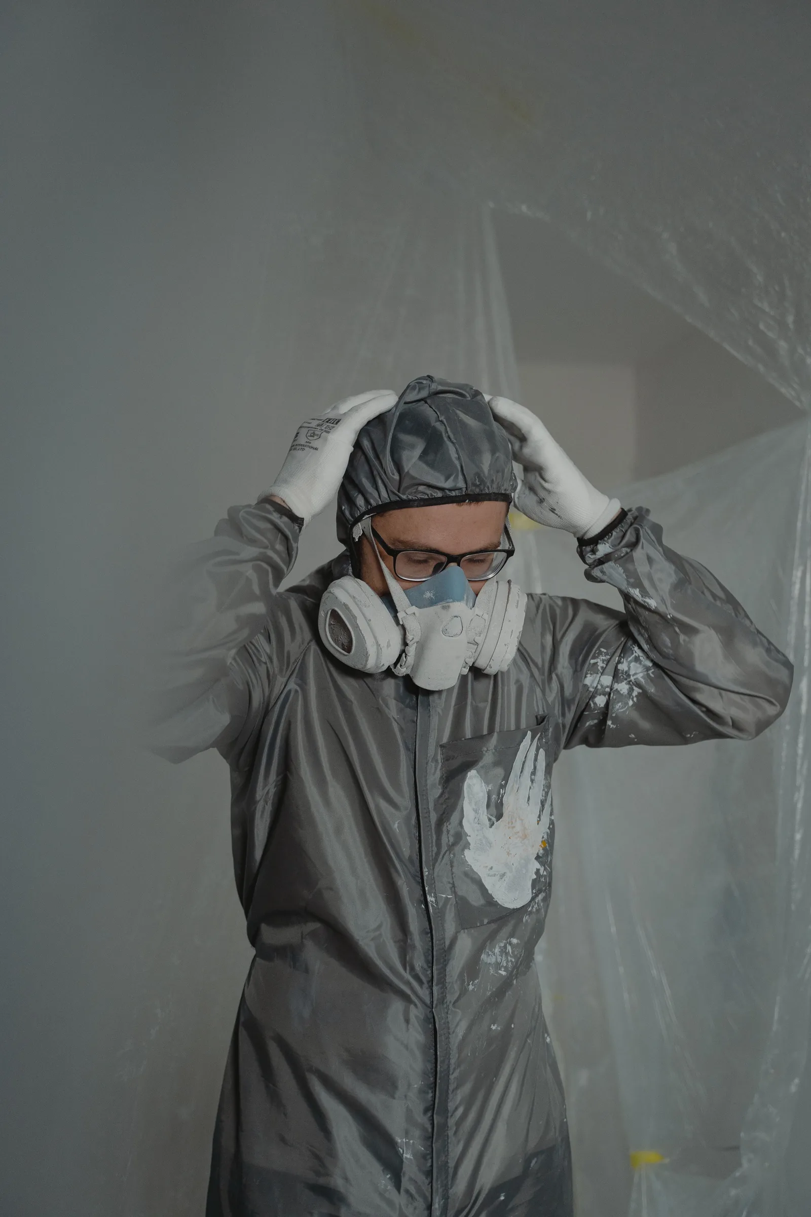 Technician in full protective coveralls and respirator inside a sealed plastic containment barrier during a mold remediation job